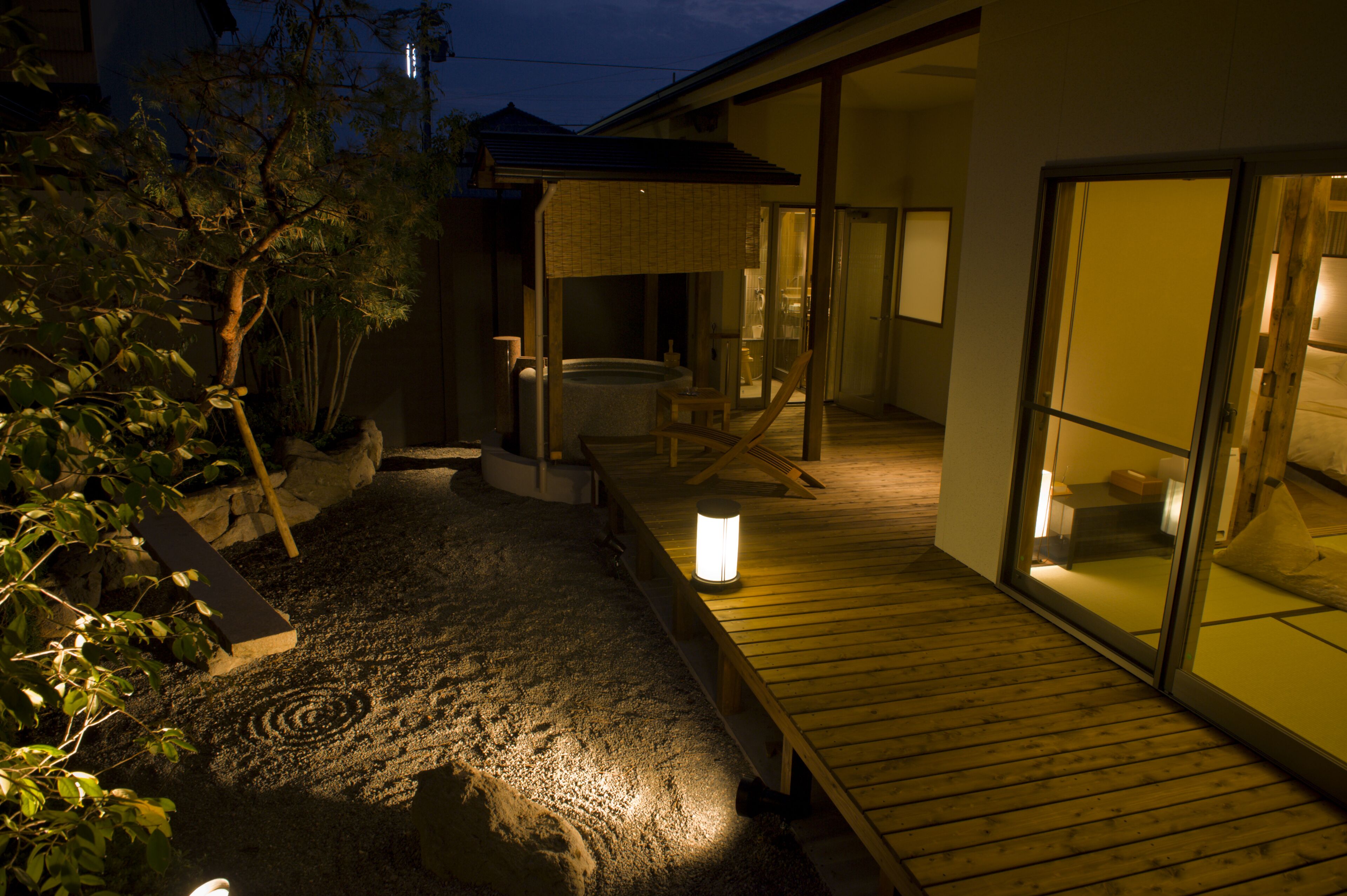 A traditional Japanese-style house with a hot spring, wooden deck, and sliding doors.