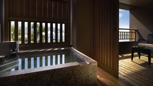 A stone hot tub with a wooden deck and a view of the city. - Migiwaya (Yaizu)