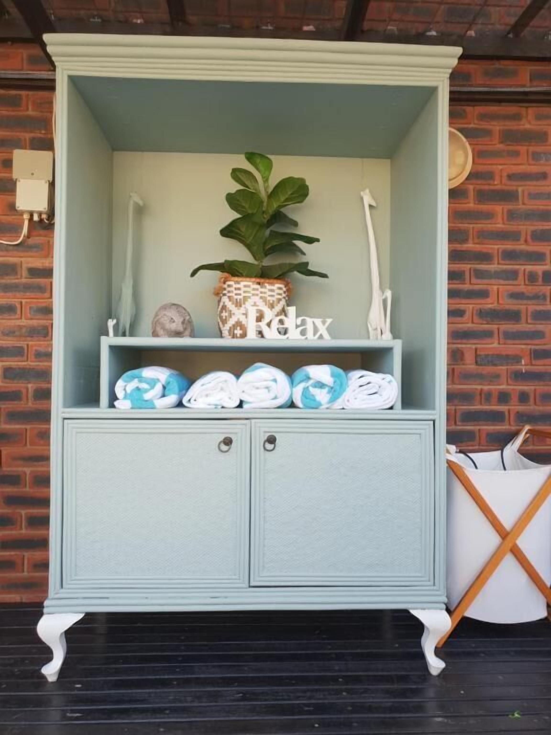 A light blue cabinet with a plant, a 'Relax' sign, and rolled towels.