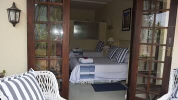 Un dormitorio con una cama grande, dos mesitas de noche, una ventana y una puerta que da a otra habitación.