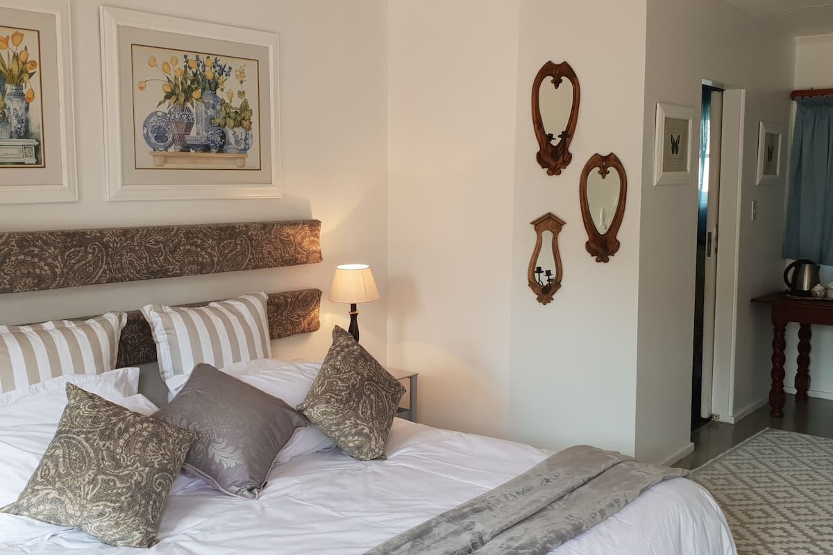 A neatly made bed with patterned pillows, a bedside table with a lamp, and wall-mounted mirrors.