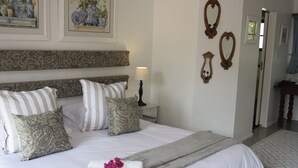 A neatly arranged bedroom with a large bed, decorative pillows, a bedside table with a lamp, and wall-mounted mirrors. - Berkeley House (Durban North)