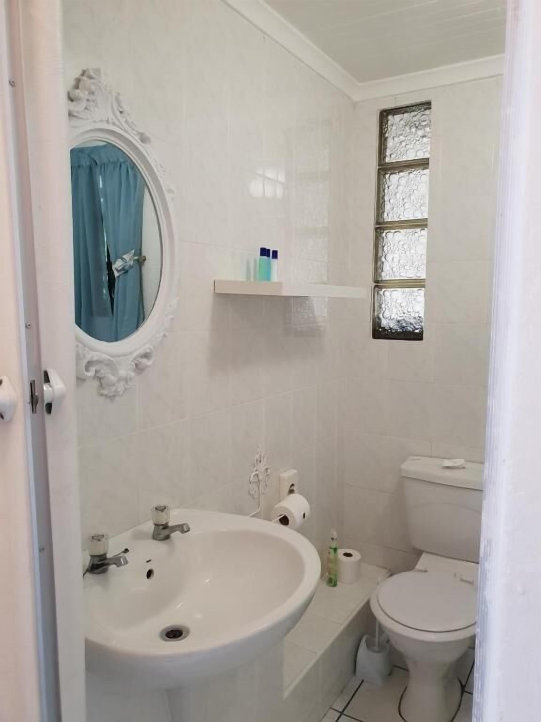 Une salle de bain équipée d’un lavabo, de toilettes et d’une fenêtre à vitre dépolie.