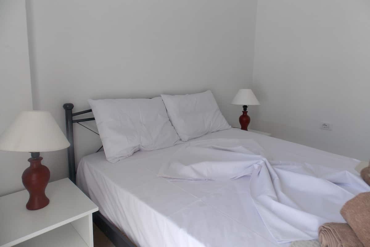 A single bed with white bedding, two bedside lamps, and a small bedside table.