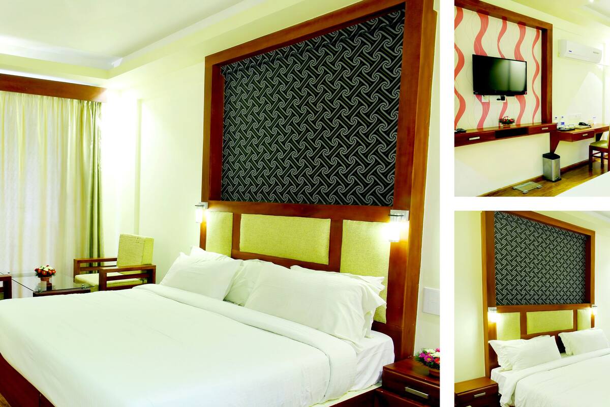 A hotel room with a large bed, a desk with a chair, a television, and a bathroom.