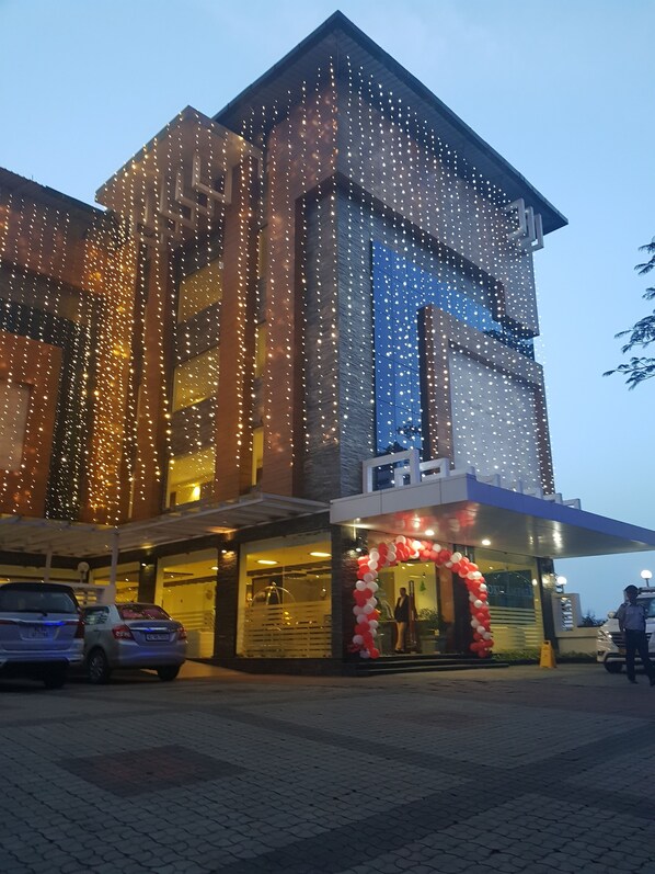 A modern building with a glass facade and string lights. - Gokulam Park Munnar (Devikolam)