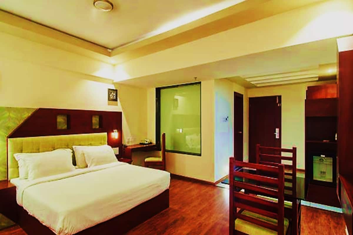 A hotel room with a bed, a desk, a chair, and a large window.