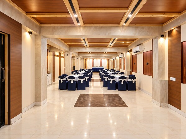 A conference room with rows of tables and chairs, wooden ceiling beams, and marble flooring. - Hotel Arya Palace (Bhubaneshwar)