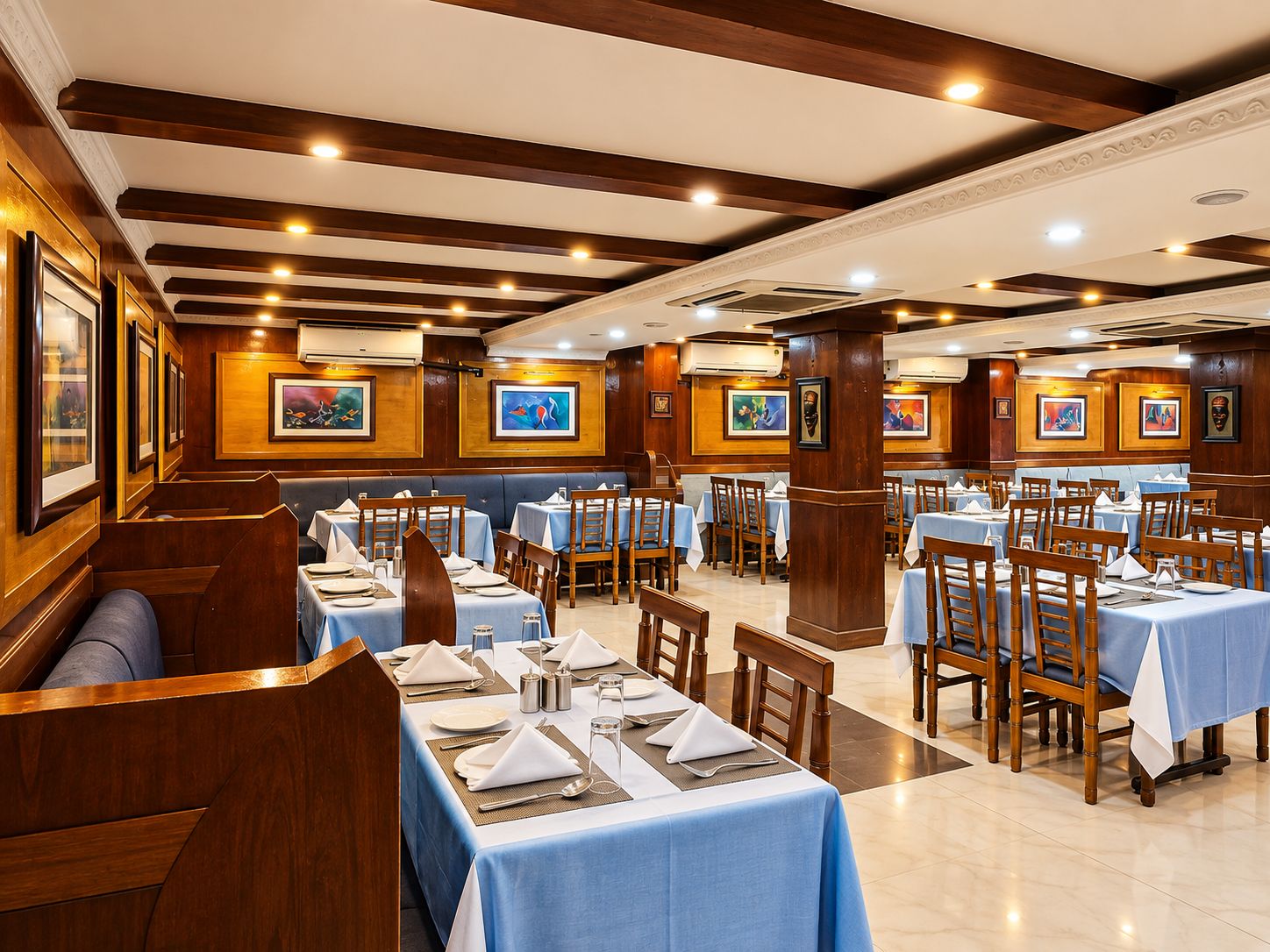 Un restaurante con varias mesas dispuestas para comer, paneles de madera en las paredes y cuadros enmarcados.