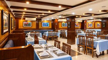 Un restaurante con varias mesas dispuestas para comer, paneles de madera en las paredes y cuadros enmarcados.