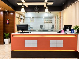 A hotel reception desk with a computer, a clock, and a fire extinguisher.