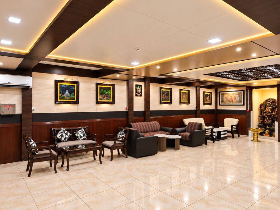 Un vestíbulo de hotel con mostrador de recepción, zona de estar con sofás y sillones, y obras de arte colgadas en la pared.
