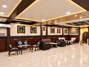 Un vestíbulo de hotel con mostrador de recepción, zona de estar con sofás y sillones, y obras de arte colgadas en la pared.