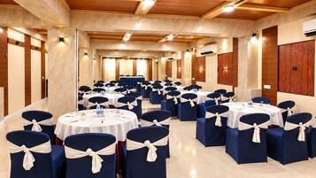 Un salón de conferencias con mesas y sillas redondas, dispuestas en filas.