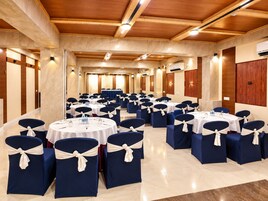 Un salón de conferencias con mesas y sillas redondas, dispuestas en filas.