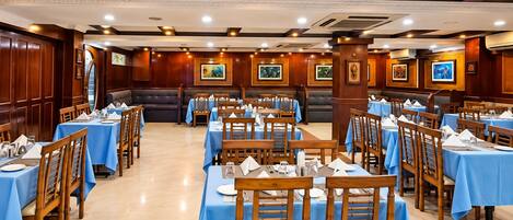 Un restaurante con varias mesas y cabinas, sillas de madera y manteles azules.