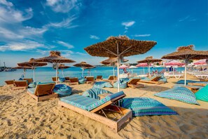 A beach with wooden lounge chairs and thatched umbrellas, a clear blue sky, and a calm sea. - Esteban VIP Residence Club (Nessebar)