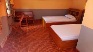 Una habitación pequeña y acogedora con dos camas de madera, un banco de madera y una mesita.