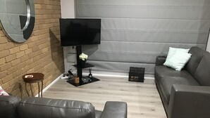 A modern living room with a grey sofa, a black TV stand with a flower vase, and a small table with a candle. - Grantian, Bacchus Marsh (Bacchus Marsh)