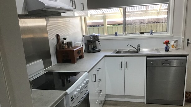A modern kitchen with stainless steel appliances, white cabinetry, and a window overlooking a garden. - Grantian, Bacchus Marsh (Bacchus Marsh)