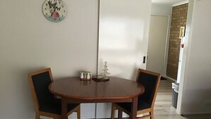 A dining area with a round wooden table and two chairs, a wall clock, and a small decorative item on the table. - Grantian, Bacchus Marsh (Bacchus Marsh)