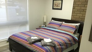 A neatly made bed with a striped bedspread, a pillow, and a folded towel on the bed. - Grantian, Bacchus Marsh (Bacchus Marsh)