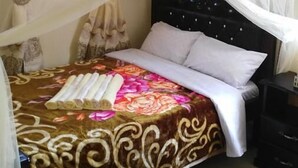 Una cama con dosel, una mesita de noche y un edredón estampado.