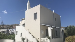 A modern two-story building with a white facade, a small staircase leading to the entrance, and a satellite dish on the roof. - Villa Katerina (Syros)