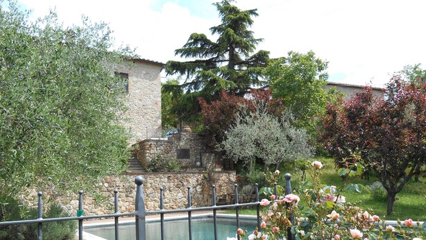A stone building with a pool and a garden with roses.