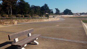 Un parc avec un banc en bois, des allées de gravier, des murs de pierre et des arbres.