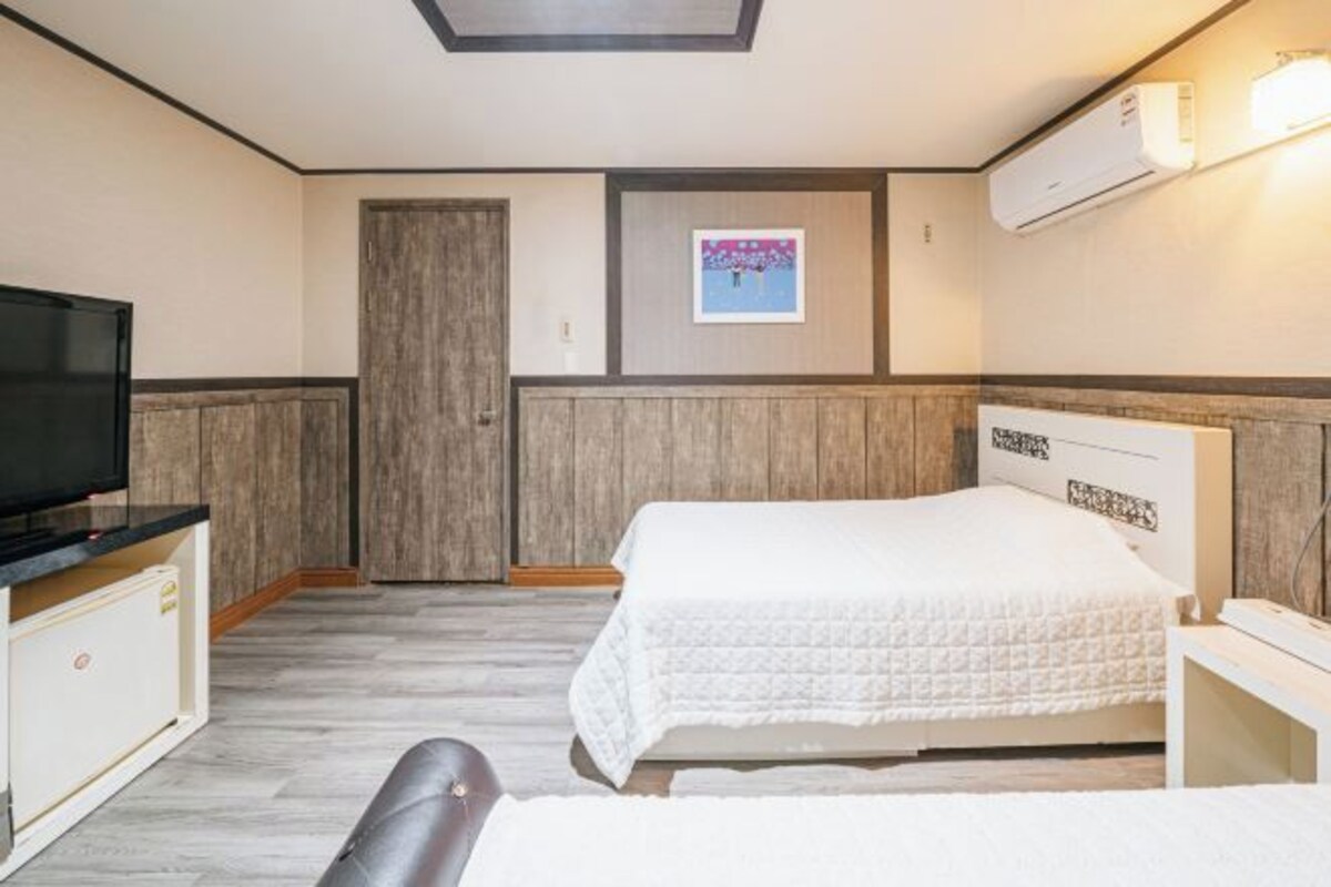 Una habitación de hotel con cama, televisión, armario y aire acondicionado.