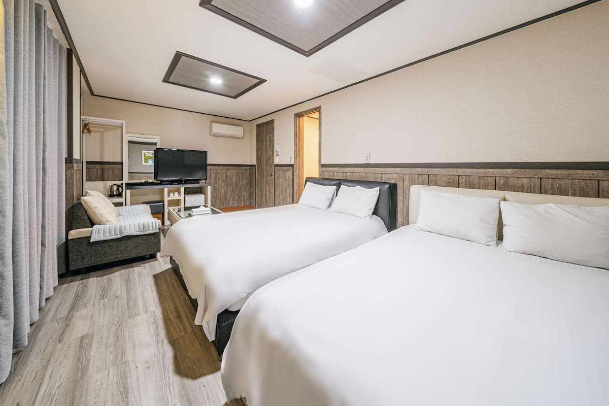 Habitación de hotel con dos camas, televisión, escritorio y armario.