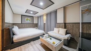 Una habitación de hotel moderna con una cama, un sofá, una mesita de vidrio y un armario.
