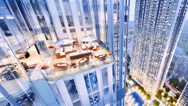 Un edificio alto con un área de lounge en la azotea, que cuenta con asientos exteriores y barandilla de vidrio.