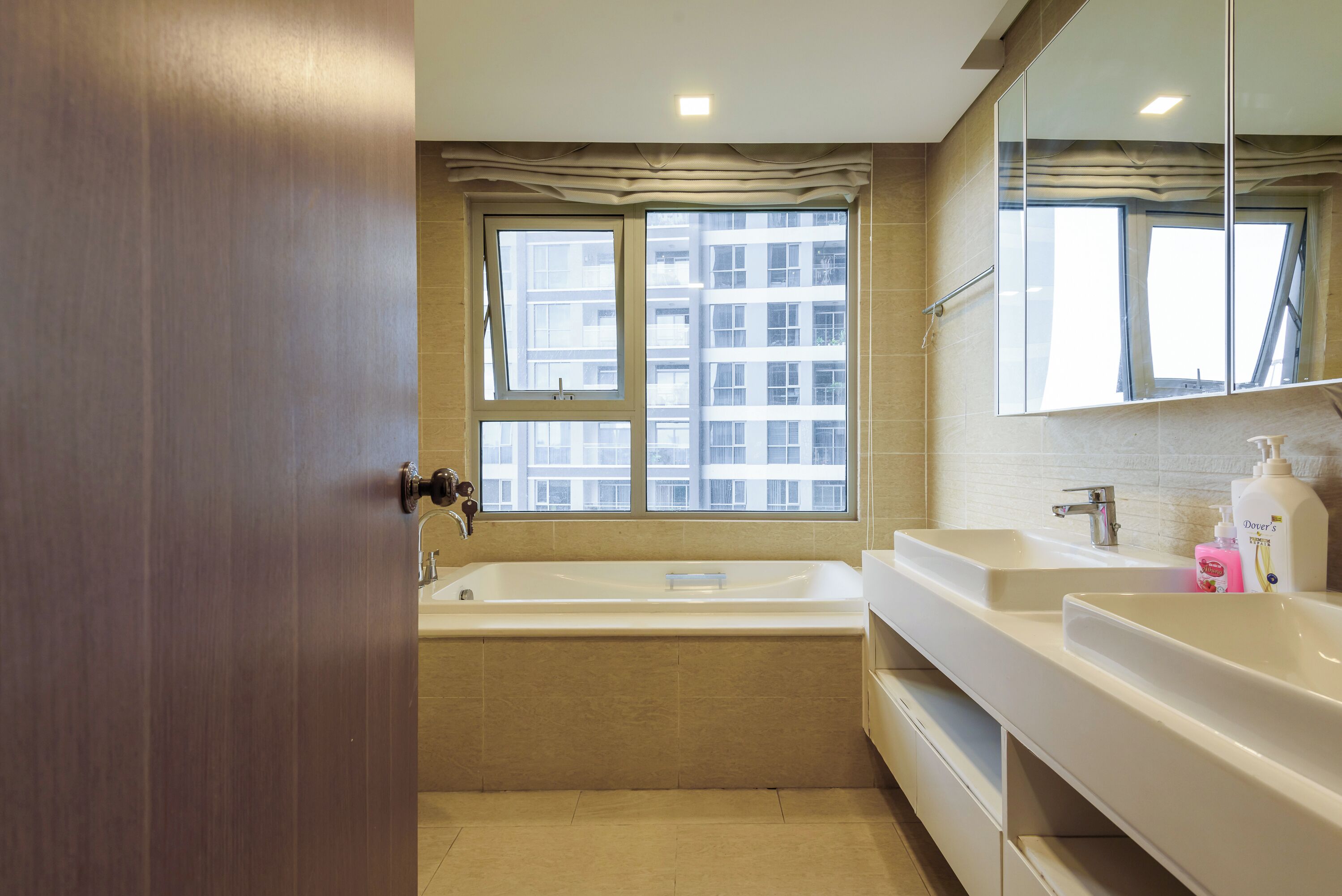 A modern bathroom with a bathtub, two sinks, and a large mirror.