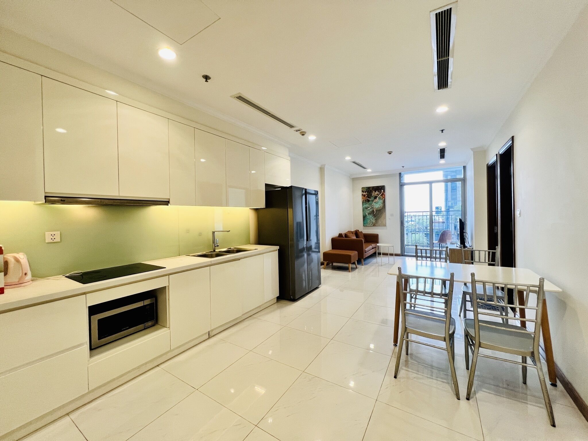A modern kitchen with white cabinets, a black refrigerator, and a dining area with a table and chairs.