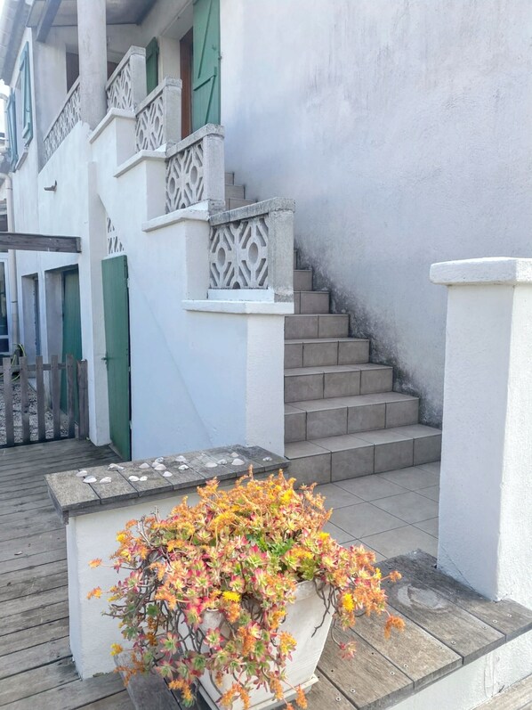 A staircase with white railings and a planter with colorful flowers at the base. - Homerez - House in Agde with Garden. (Agde)