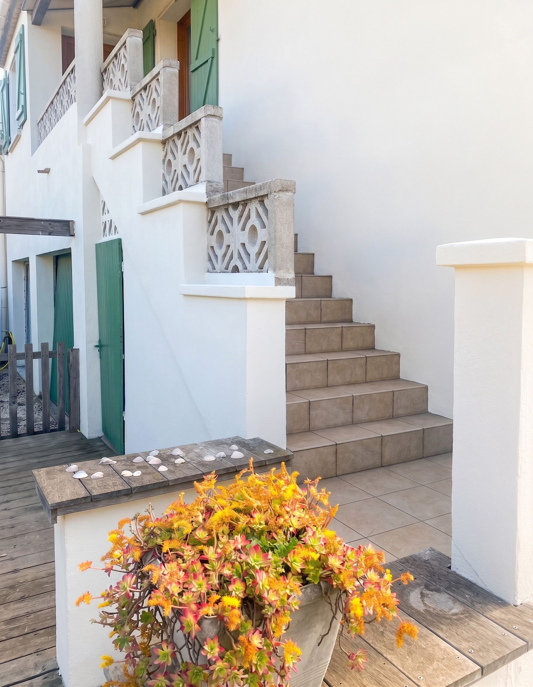 A staircase with a white railing and a planter with flowers at the bottom.
