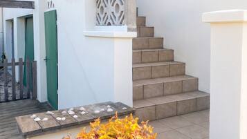 A staircase with a white railing and a planter with flowers at the bottom.