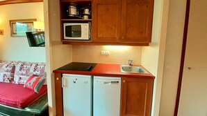 Una cocina compacta con armarios de madera, un microondas, un lavamanos y dos lavavajillas blancos.
