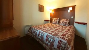 Un dormitorio con una cama grande, un cabecero con luces empotradas y una mesita de noche pequeña.