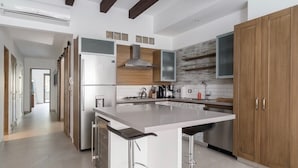 A modern kitchen with a central island, stainless steel appliances, and wooden cabinetry. - Modern Hideaway with Private Terrace in Old Town (Puerto Vallarta)