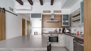 A modern kitchen with a central island, built-in appliances, and a wooden accent wall. - Modern Hideaway with Private Terrace in Old Town (Puerto Vallarta)