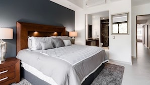 A modern bedroom with a large bed, bedside lamps, and a dark blue accent wall. - Modern Hideaway with Private Terrace in Old Town (Puerto Vallarta)