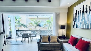 A modern living room with a sofa, a dining area, and a balcony with plants. - Modern Hideaway with Private Terrace in Old Town (Puerto Vallarta)