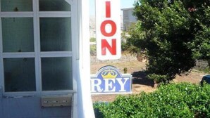 A building with a sign that reads "PENSION REY" and a window with a white frame. - Pensión Rey (Isla de Arosa)