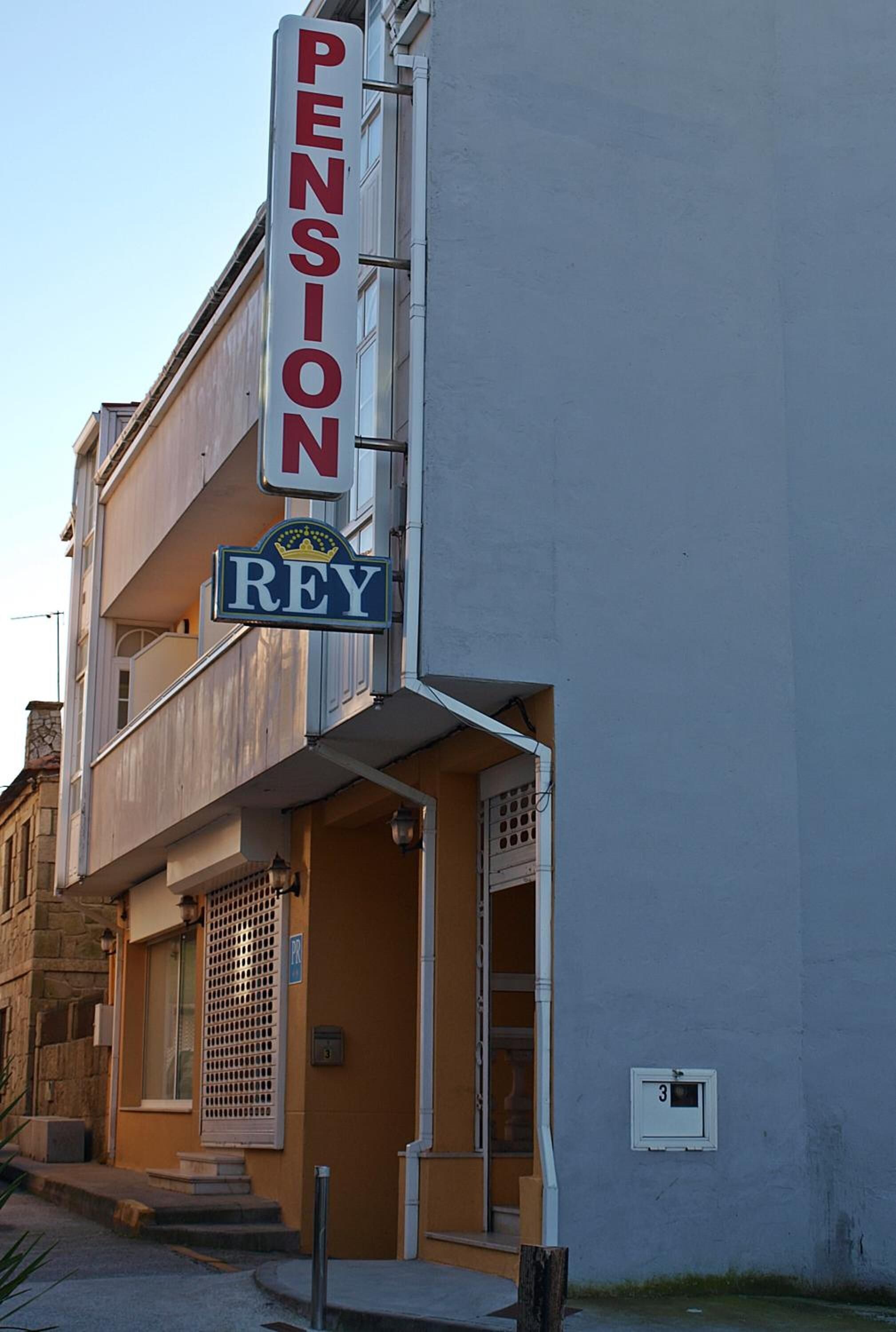 Un edificio con un letrero que dice "PENSION REY" y un balcón.