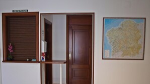 A reception area with a closed shutter, a door, and a map on the wall. - Pensión Rey (Isla de Arosa)