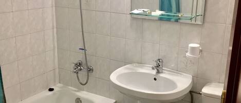 A bathroom with a bathtub, a sink, a toilet, and a mirror.