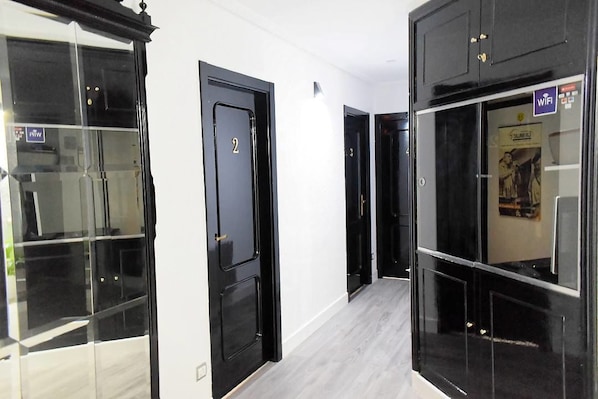 A hallway with black doors, each marked with a number. - Alojamientos Puerto Príncipe (Santander)